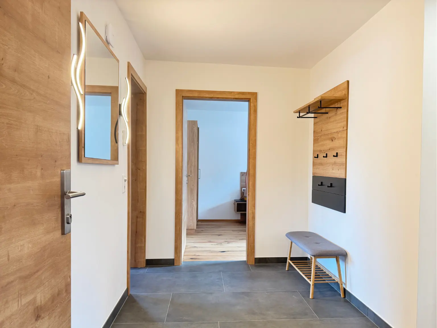 Eingangsbereich des 82 m² Apartments mit Holzakzenten und Sitzbank