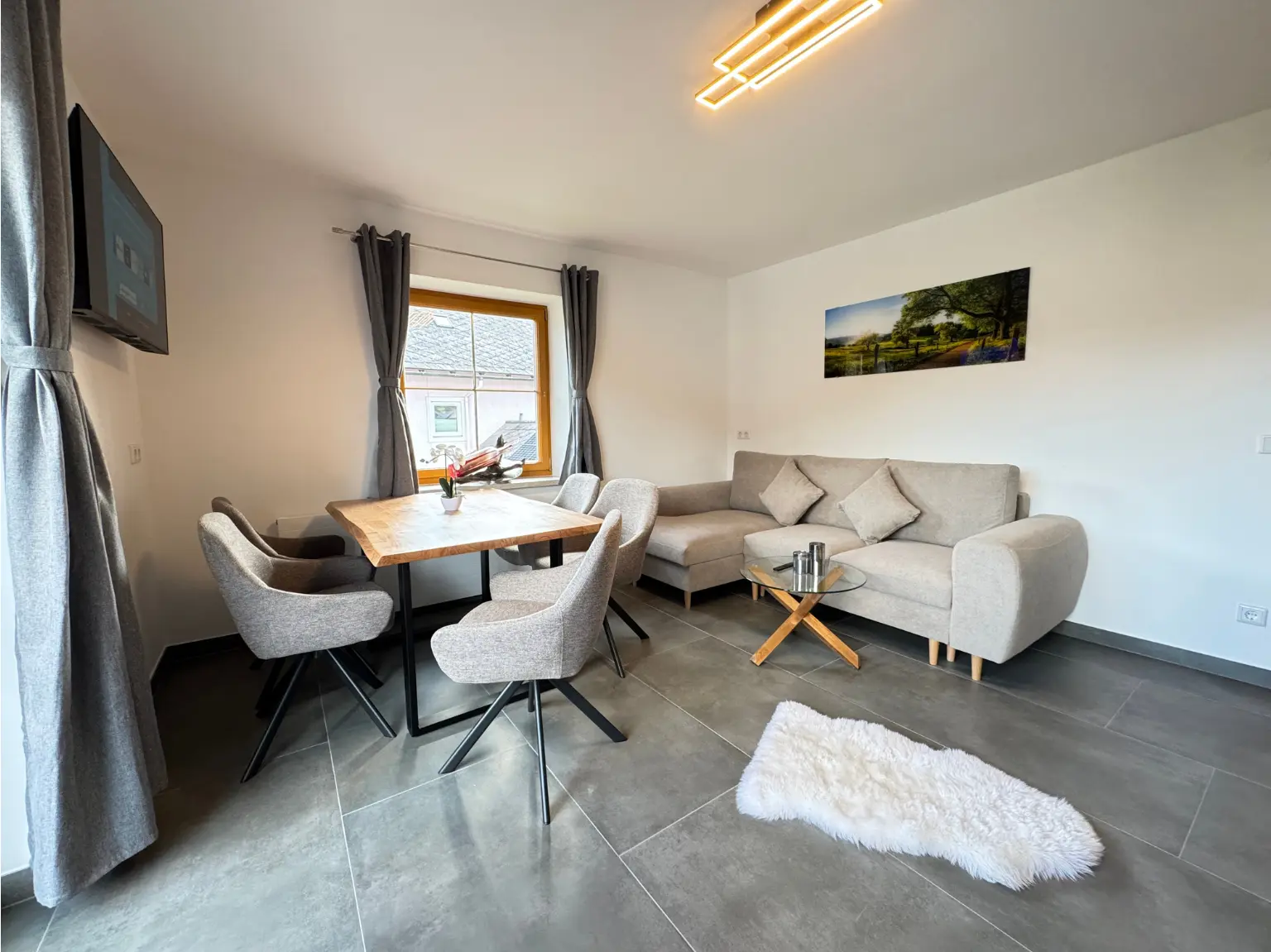 Heller Wohnbereich des 82 m² Apartments mit Kitchenette und Balkontür