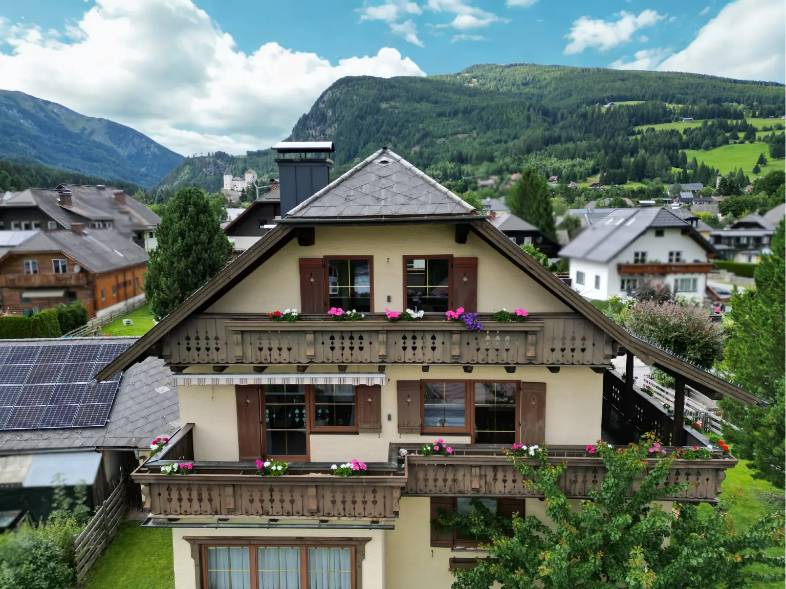 Außenansicht des Hauses mit Balkonen, Blumen und Bergpanorama