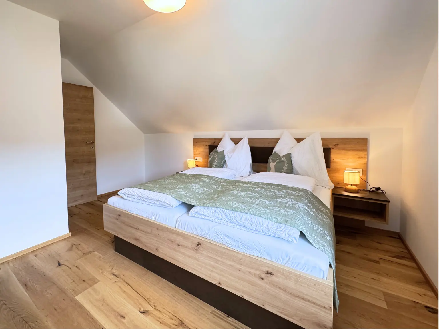 Schlafzimmer mit Doppelbett, Holzboden und Nachttischleuchten
